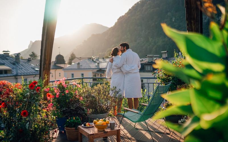 Ein Paar im Bademantel auf der Terrasse des Hotels und Villa Auersperg Salzburg stehend und sich küssend