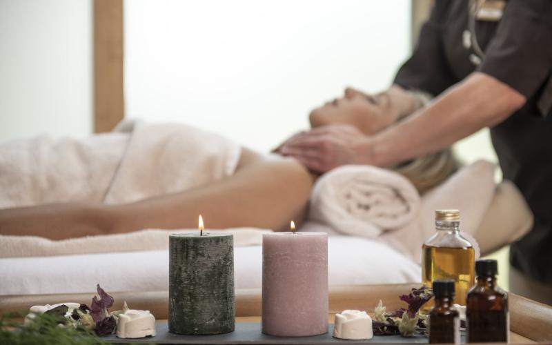Eine Dame genießt eine Nackenmassage im Wellnessbereich des Waldhof Fuschlsee Resort