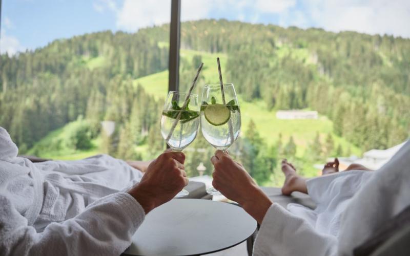 Zwei Gäste im Bademantel prosten einander zu im Sporthotel Wagrain