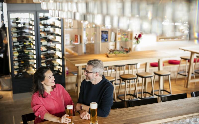 Zwei Gäste mit einem Bier an der Bar im ARCOTEL Nike Linz