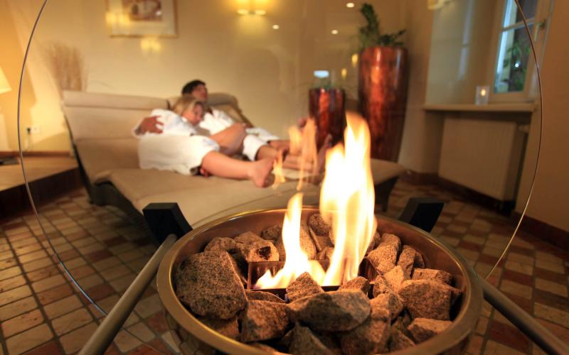Zwei Gäste kuscheln im Ruheraum mit offenem Kamin im Romantik Hotel Im Weissen Rössl