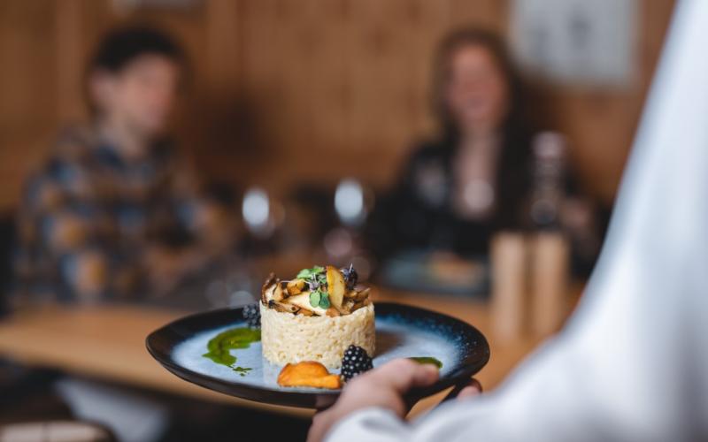 Eine Servicekraft bringt ein Dessert im Restaurant des DAS WALCHSEE Sportresorts