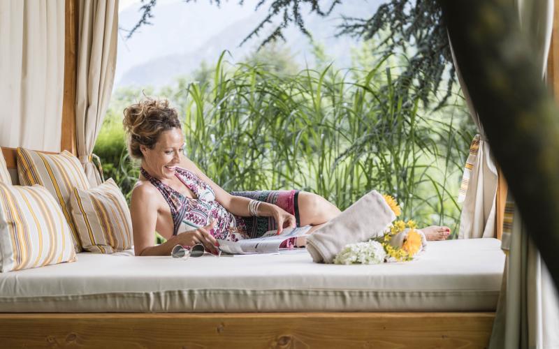 Eine Frau beim Lesen auf einer Entspannungsliege im Romantik Hotel Stafler