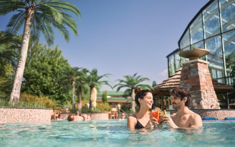 Zwei Gäste im Aussenpool mit einem Cocktail im EurothermenResort Bad Schallerbach Hotel Paradiso ****S