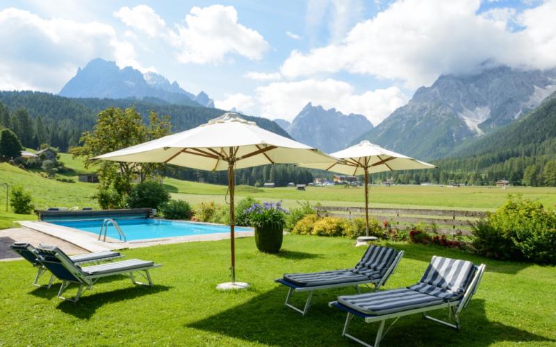 Garten des Hotels Drei Zinnen mit Schwimmbad und Liegen