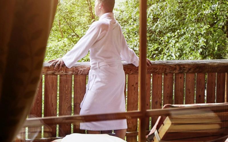 Ein Mann steht am Balkon des Saunadorfes im DAS RONACHER Thermal und Spa Resort