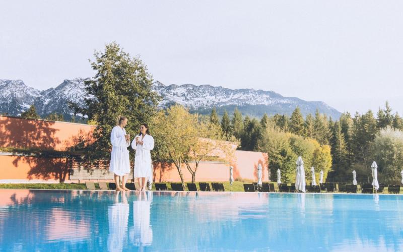 Paar steht mit Bademantel am Pool