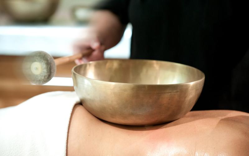 Ein Gast bei einer Klangschalenbehandlung im Wellnessbereich des Impuls Hotels Tirol