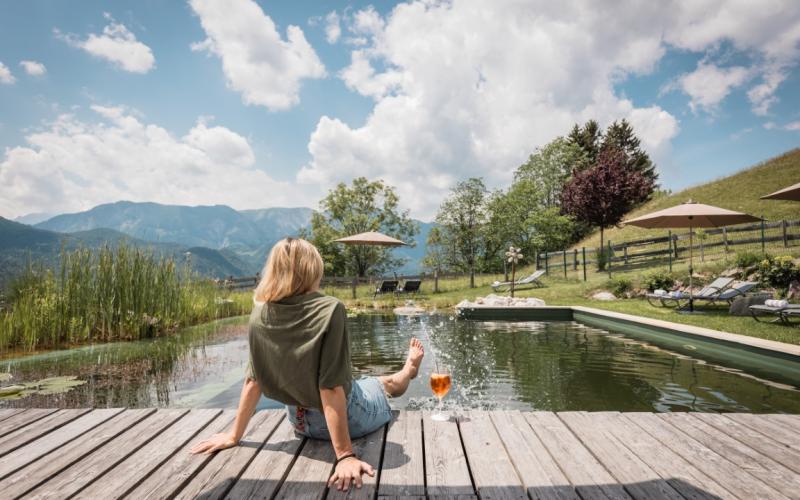Eine Dame sitzt am Schwimmteich des Naturhotels Landhof Irschen