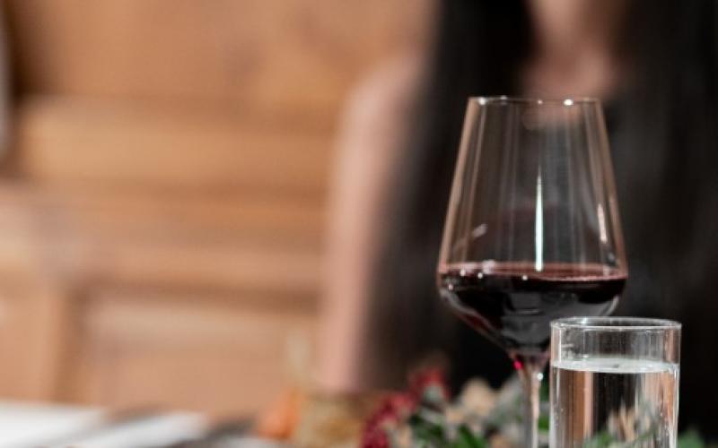 Ein weiblicher Gast sitzt bei gedecktem Tisch im Restaurant des Hotels Kohlerhof