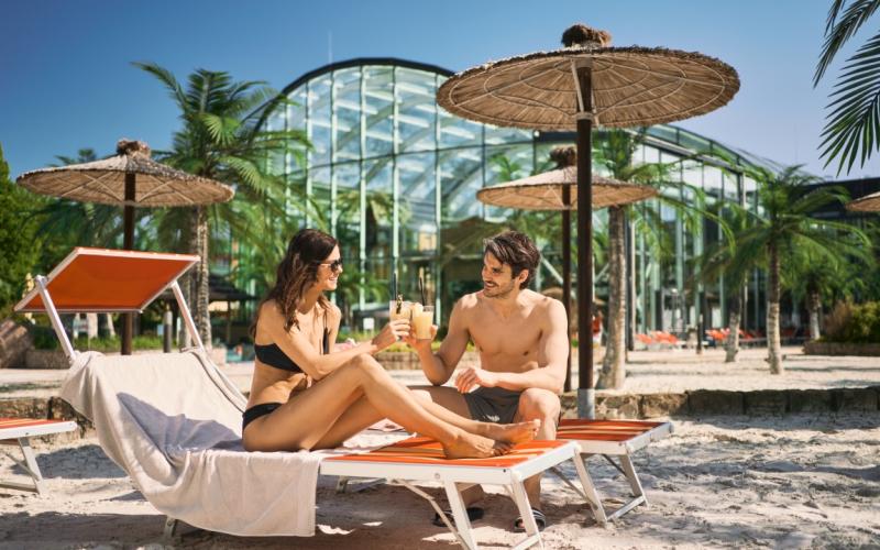 Ein Paar mit einem Getränk auf den Sonnenliegen im Aussenbereich des EurothermenResort Bad Schallerbach Hotel Paradiso