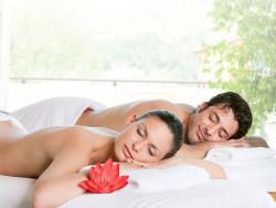 Ein junges Paar entspannt mit geschlossenen augen nebeneinander auf Massageliegen