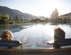 Zwei Gäste liegen im Aussenpool mit Blick auf die Umgebung im Waldhof Fuschlsee Resort