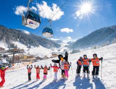 Eine Kinder-Schigruppe auf der Piste mit Blick auf die Gondeln beim Familienhotel Zauchenseehof