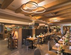 Blick in das modern gestaltete Restaurant mit gedeckten Tischen im Aktivhotel Alpendorf