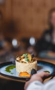 Eine Servicekraft bringt ein Dessert im Restaurant des DAS WALCHSEE Sportresorts