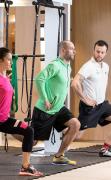 Zwei Gäste trainieren mit einem Personal Trainer im Fitnessbereich des Das Hohe Salve Sportresorts
