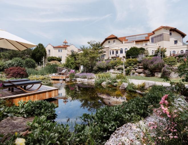 Aussenansicht mit Badeteich und Liegen im Vordergrund des Hotels Bergergut