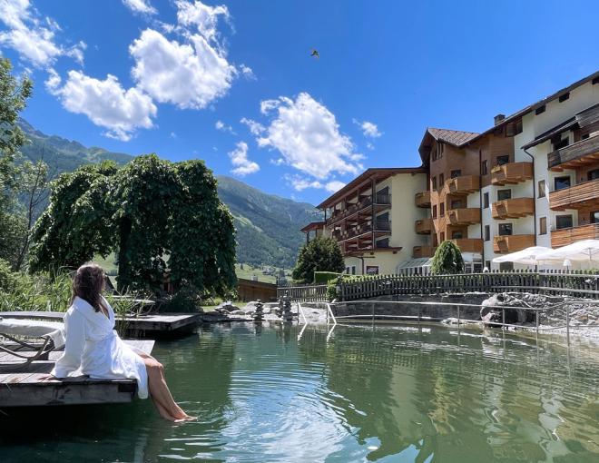 Eine Dame sitzt im Bademantel am Naturteich des Naturhotels Outside